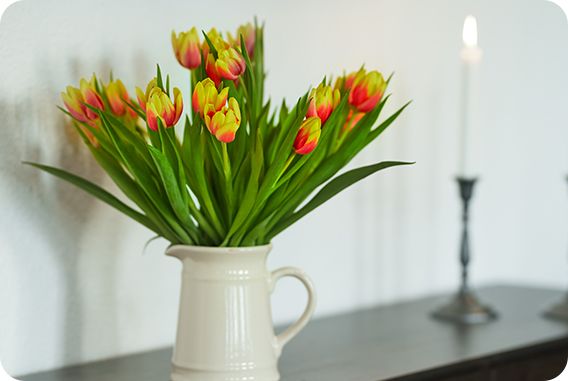 Joli bouquet de fleurs dans un pot blanc sur un meuble noir laqué